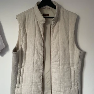 Beige quiltad väst från Stenströms - Snygg beige quiltad väst från Stenströms. Västen har en stilren design med hög krage och dragkedja framtill. Perfekt för lager-på-lager under kyligare dagar.