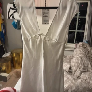 Vit Zara klänning  - Snygg kort vit satin klänning med v-ringning. Perfekt för sommaren och studenten. Helt oanvänd med prislapp kvar ❤️