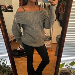 Grå offshoulder tröja från Nelly - Säljer en snygg grå offshoulder tröja från Nelly. Tröjan är stickad och har en ribbad design som ger en stilren look. . 