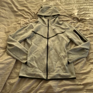 Grå nike tech fleece  - Säljer min tech fleece då den inte kommer till användning har haft den i typ 3 månader men använt den väldigt sällan. Skulle säga 6-10 gånger. Inga tecken på användning nånstans så den är i nyskick. Kan tänka mig att den är schysst att ha till en väst nu till våren