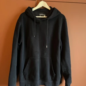 Mörkblå hoodie - Säljer en stilren mörkblå hoodie från Sustainable Clothing Essentials. Den har en klassisk design med huva och dragsko samt en praktisk magficka. 