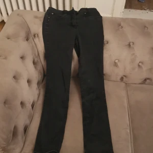 Svarta slim jeans från Brandtex - Snygga svarta slim jeans från Brandtex med klassisk femficksdesign och knappar i silver. Tillverkade i en bomullsblandning för komfort och stil. Perfekta för en stilren look.