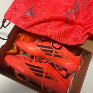 Adidas f50 ag/fg storlek 42 - Snygga röda fotbollsskor från Adidas med svarta detaljer. Skorna har snörning och är designade för optimal prestanda på planen. Perfekta för fotbollsspelare som vill sticka ut. Köpta från stadium för 2999 kr och är helt nya. Passade inte mig och därför så säljer jag mig av dom här på Plick. 