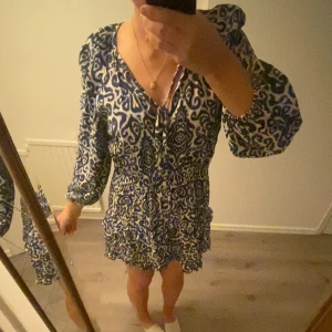 Mönstrad klänning från Zara🤍🤍 - Säljer en snygg mönstrad klänning från Zara i blått och vitt. Klänningen har en v-ringad design med långa ärmar. Perfekt för att sticka ut med stil! 💙