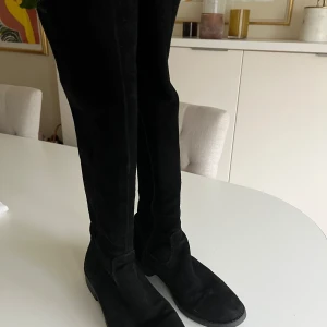 Svarta mockastövlar med dragkedja - Snygga svarta stövlar i mocka med dragkedja på sidan. Perfekta för höst och vinter, dessa stövlar har en klassisk design som passar till många olika outfits.