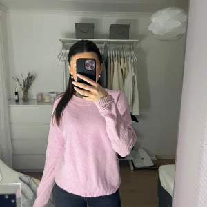 Rosa stickad tröja - Mysig rosa stickad tröja med rund hals och långa ärmar. Perfekt för kyligare dagar och ger en avslappnad look. Passar bra till jeans eller kjol för en stilren outfit.