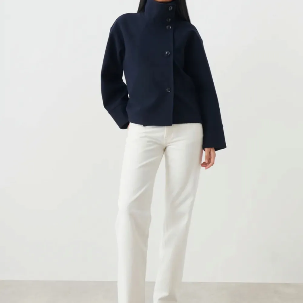 Snygg svart kavaj med hög krage och knappar framtill. Den har en stilren design med långa ärmar och en rak passform. Perfekt för en elegant look.. Takit.