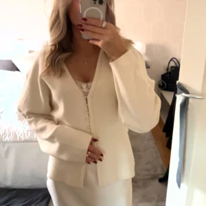 Vit/Beige kofta med knappar - Säljer en stilren beige kofta med knappar framtill. Koftan har en v-ringad design och långa ärmar som går in i midjan, perfekt för en elegant look. Passar bra till både vardag och speciella tillfällen. Strl M men passar mig som brukar ha xs-s!❤️ köpte i höstas 🥰
