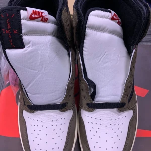 Nike Air sneakers med Cactus Jack-detaljer - Säljer ett par grymma Nike Air sneakers med Cactus Jack-detaljer. Skorna har en snygg kombination av vitt och brunt med svarta detaljer. De är i nyskick och har en cool design med den klassiska Nike-loggan på sidan. Perfekta för både vardag och fest!