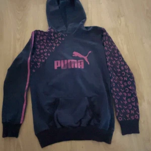Svart och rosa hoodie från Puma - Säljer en snygg svart hoodie samt byxor från Puma med rosa detaljer. Den har ett stort Puma-tryck på framsidan och baksida. Helt nytt skick, kan mötas upp. Sjukt bra pris!!! Fint för barnen eller för tonåringen(: