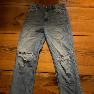 Blå jeans från FB Sister - Säljer ett par blå jeans från FB Sister i storlek L. De har en klassisk femficksdesign och slitna detaljer på framsidan. Perfekta för en avslappnad stil.