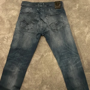 Blå jeans från Replay - Snygga blå jeans från Replay med en klassisk femficksdesign och diskreta slitningar. De har en knappgylf och märkeslogga på baksidan. Perfekta för en avslappnad stil.  Kan ändra priset vid snabb förhandling!