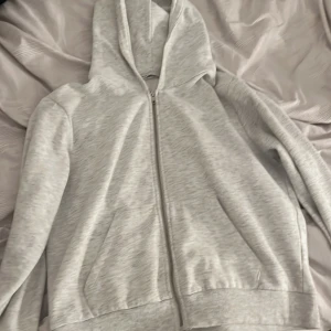 Grå hoodie med dragkedja - Säljer en bekväm och stilren grå hoodie med dragkedja. Perfekt för en avslappnad look. Den har långa ärmar och en praktisk huva.