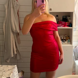 Röd glittrig offshoulder klänning superDown märke köptes för 1500 - Snygg röd offshoulder klänning med glittrande detaljer. Perfekt för en festlig kväll. Klänningen är tight och kort, vilket ger en elegant och stilren look. Superform märke
