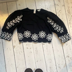 Svart blus med broderade blommor från H&M - Säljer min svarta hm blus då den är för liten❤️har bara används två gånger och är därför i väldigt bra skick 💕🩷kostade 299 kr från början 💖