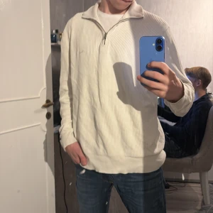 Vit tröja med dragkedja från Gant - Säljer en stilren vit tröja från Gant med dragkedja och ribbad struktur. Perfekt för en avslappnad look. Tröjan har långa ärmar och en hög krage. Nypris 1500. 10/10 använd två gånger på grund av den var för stor för mig 