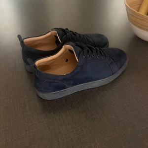 Mörkblå Christin Louboutin sneakers  - Snygga mörkblå sneakers med en röd sula. Skorna har tagits hand om väl vid användning.