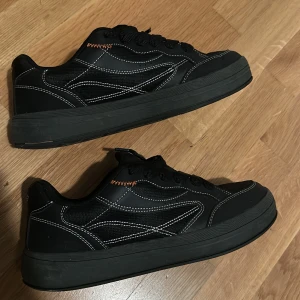 Svarta sneakers  - (Tåkappan på den högra skorn är skadad men det är något som man kan fixa). Snygga svarta sneakers från Bershka med vita sömmar och snörning. Perfekta för en casual look med en robust sula och stilren design.