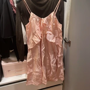 Ljusrosa klänning från H&M Divided - Söt ljusrosa klänning med smala axelband och volangdetaljer framtill. Perfekt för varma dagar eller som ett lagerplagg. Enkel och stilren design som ger en romantisk känsla.