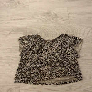 Leopardmönstrad topp från Kappahl - Säljer en cool leopardmönstrad topp från Kappahl i storlek 134. Toppen har korta ärmar och är perfekt för en trendig look. Materialet är mjukt och bekvämt, vilket gör den idealisk för vardagsbruk.