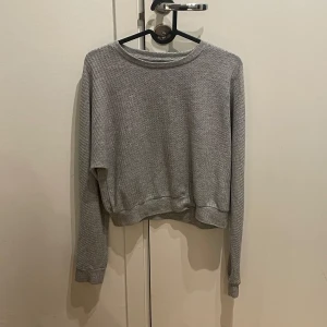 Grå tröja - Säljer en enkel och bekväm grå tröja med rund hals och långa ärmar. Perfekt för en avslappnad stil.