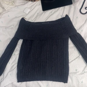 Svart stickad offshoulder tröja - Säljer en snygg svart stickad offshoulder tröja. Perfekt för kyliga dagar med sin ribbade design och långa ärmar. Passar både till jeans och kjol för en stilren look.