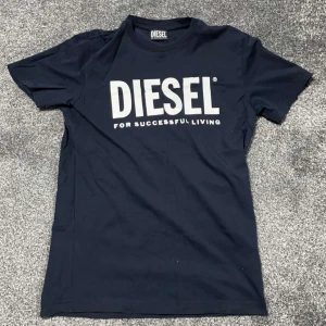 Mörkblå t-shirt från Diesel - Snygg mörkblå t-shirt från Diesel med stort vitt tryck på framsidan. T-shirten är köpt ifrån Kids Brand Store och är i mycket bra skick. Den är i storlek S. 