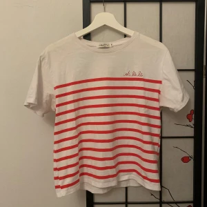 Vit och röd randig t-shirt från Emi-Jo - Vit t-shirt med röda ränder och texten 'oh la la' broderad på bröstet. Köpt i Paris, storlek S. Sparsamt använd. 