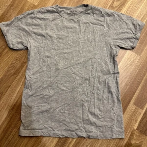 Grå t-shirt - En enkel och bekväm grå t-shirt från Newbody i storlek M. Perfekt för vardagsbruk med normal passform och korta ärmar. Oanvänd!