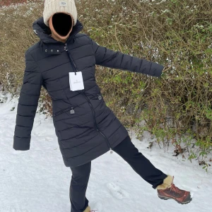 Svart dunjacka från Moncler - Säljer en svart lång dunjacka från Moncler med dragkedja och hög krage. Jackan har en fin design och är perfekt för kalla vinterdagar. Den har en stilren look och är både varm och bekväm. Personen på bilden är 165cm lång 