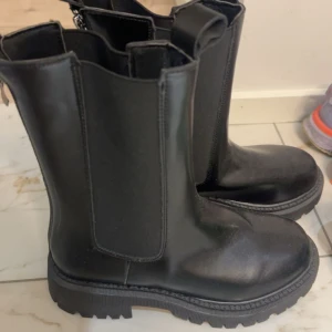 Svarta boots med dragkedja - Snygga svarta boots i skinn med dragkedja på sidan. Perfekta för höst och vinter med en robust sula som ger bra grepp. Stilren design som passar till många olika outfits.