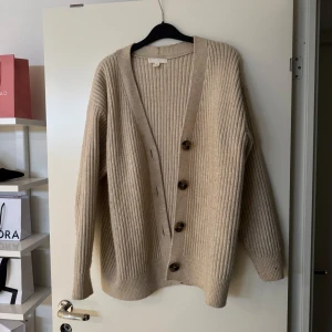 Beige stickad kofta - Mysig beige stickad kofta med stora knappar framtill. Från H&M i storlek S. Skriv privat för bilder hur den sitter på