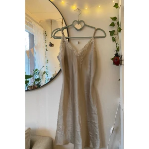 Slip dress satin - Säljer denna superfina slip dress/nattlinne i satin från Kappahl Body Zone. Den är krämvit med vita spetsdetaljer, och figurnära. Oerhört vacker och i bra skick✨köpt under tidigt 00-tal. Stl: 34/36. skriv om du har frågor :)