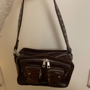 Nunoo-väska - Brun väska med silverdetaljer från Nunoo. Sparsamt använd.