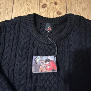 Derschutze - Senaste limited releasen från derschutze. Kabelstickad tröja i bomull med broderi av pianist på ryggen. Slutsåld på 2 minuter.