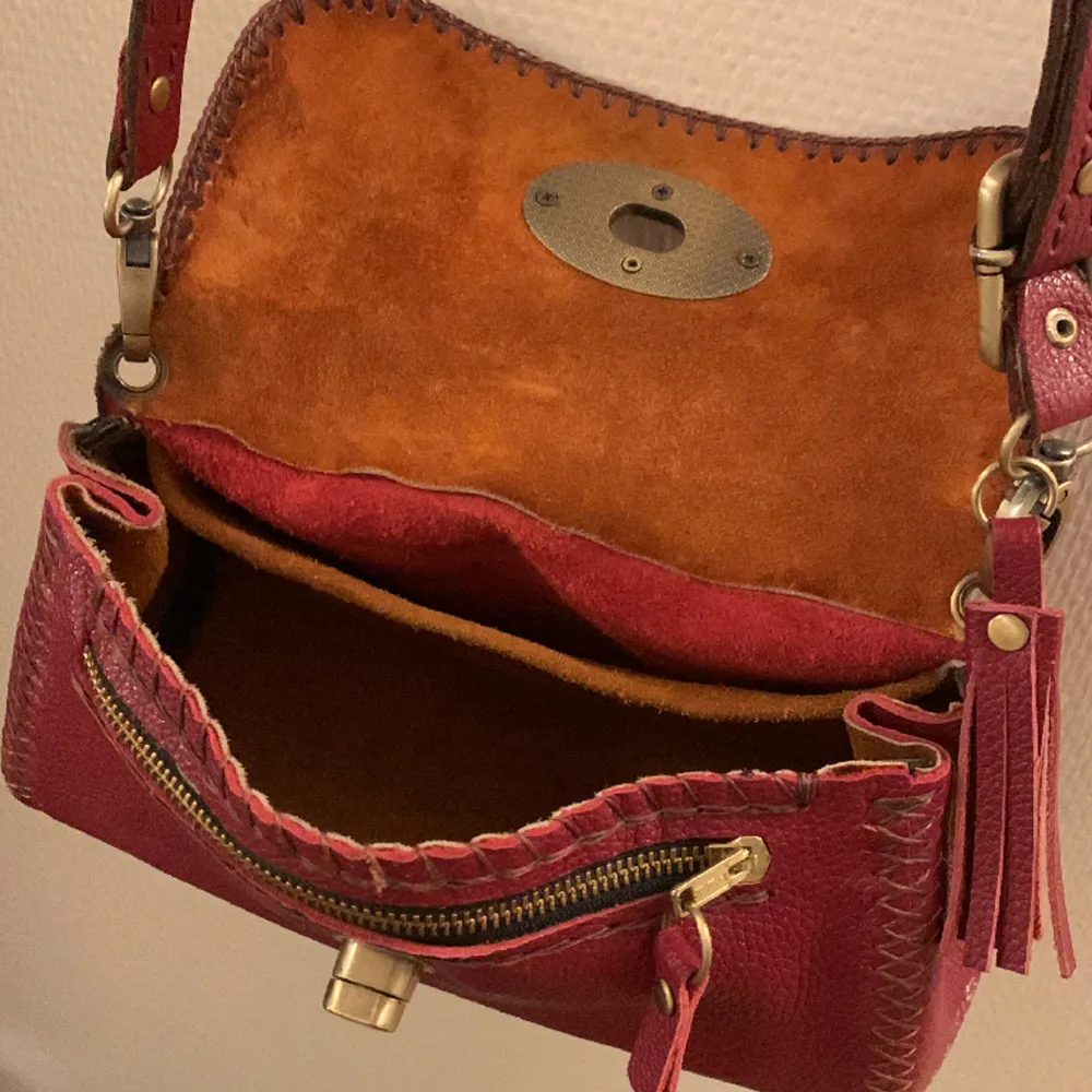 Detta är en vinröd handväska som passar för att ha småsaker T.ex tuggummipaket, mobil, plånbok,nycklar osv. Går att ändra storleken till lite större eller mindre genom knappar  och det går även att förminska eller förstora axelremsan❤️🫶👜. Väskor.