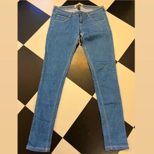 BERSHKA JEANS - Mellanblå superstretchiga stuprörsjeans. Låg midja. Storlek 38.