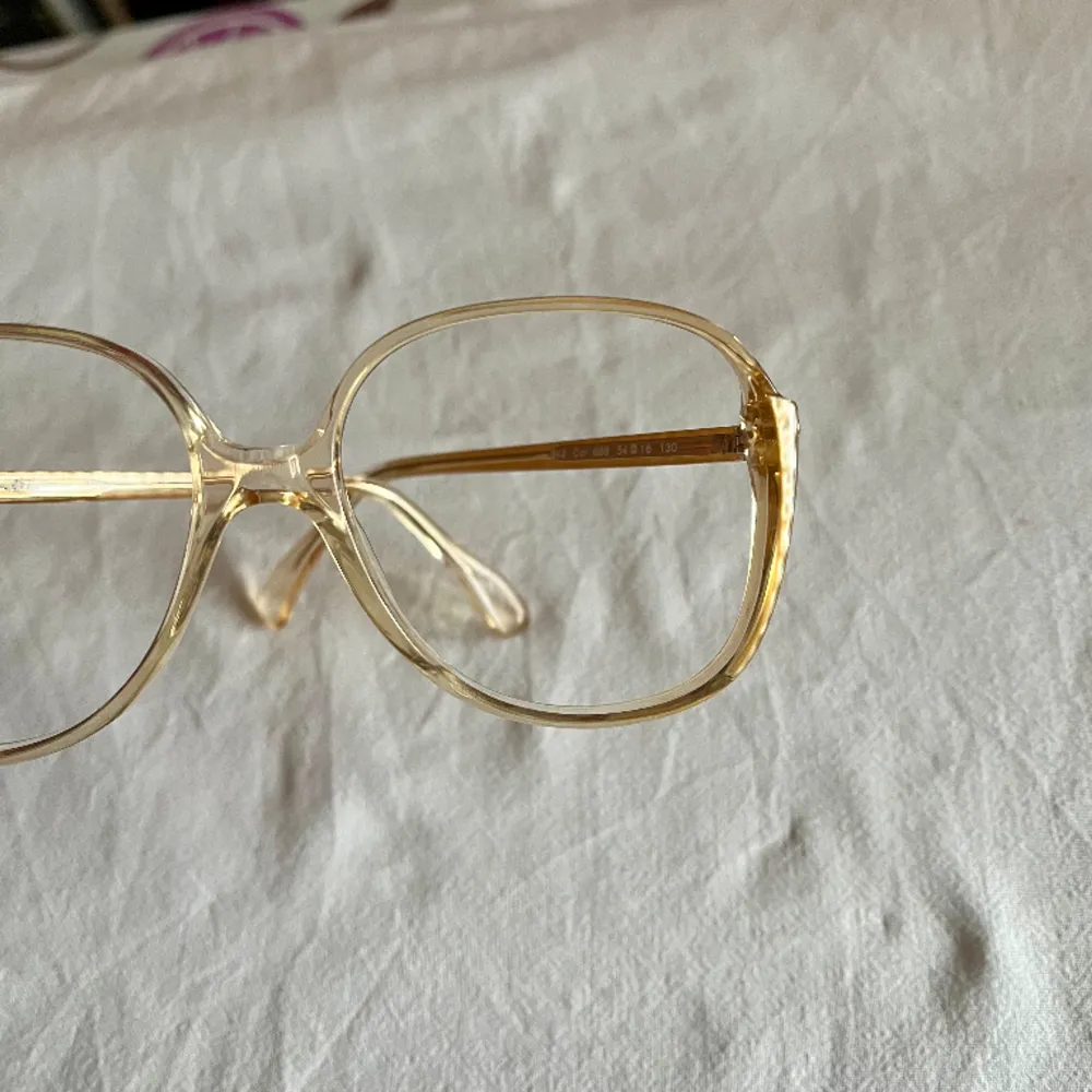 Vintage glasögonbåge från 80 talet  Kommer från en nedlagd Optikbutik, aldrig använd.  Hela bågens bredd 130 mm Glasets storlek, bredd 55 mm, djup 50 mm. Accessoarer.