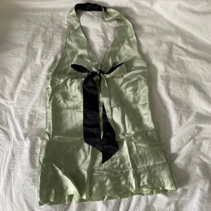 Reversible silkestopp - Halternecktopp med knytband framtill, går att bära antingen den svarta sidan ut eller den ljusgröna. En pytteliten defekt precis i v-ringningen som går att sy ihop. Inget märke eller storlek men skulle säga att den passar XS-S