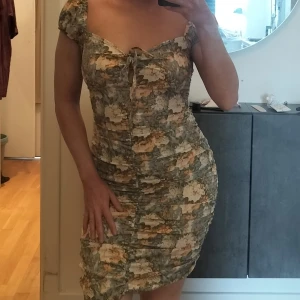 Smickrande blommig klänning - Figurnära och otroligt smickrande klänning i blommigt mönster. Färgerna stämmer bäst in på bild 2, överkroppsbilden. Stretchigt material. Passar nog bäst storlek S.