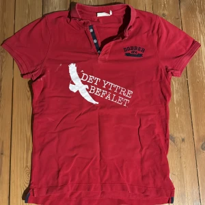 14. Röd Det Yttre Befälet Polo M - Det Yttre Befälet merch gjord av bandet själva. Polo tröjan är i bra skick.
