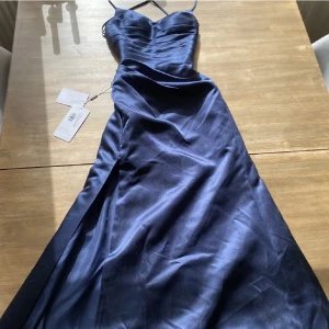 Balklänning - Jättefin balklänning. Den är mer marinblå i verkligheten och har slits och knytning i ryggen. Köpte för ca 1300kr och säljer för 800 men pris kan diskuteras. Storlek 32 men skulle säga XS/S då man kan justera banden i ryggen.