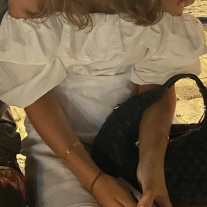 Vit off-shoulder klänning - En elegant vit off-shoulder klänning med volangdetaljer runt halsen. Klänningen har korta ärmar och en åtsittande passform.