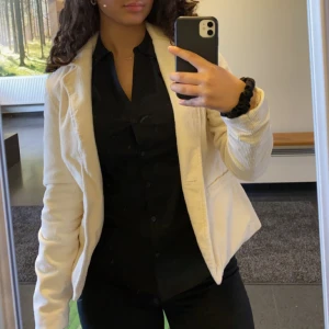 Beige kavaj från BikBok - En stilren beige kavaj från BikBok i storlek M. Kavajen har en klassisk design med krage och långa ärmar. Materialet ser ut att vara manchester, vilket ger en mjuk och bekväm känsla.