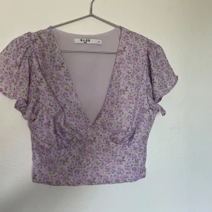 Blommig Crop top - Blommig v-ringad top, dragkedja på sidan. Fint skick!