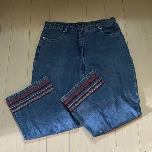 Jeans med Broderier  - Raka jeans med fina broderier längst ner. Storlek 42 men skulle säga att den passar M-L beroende på hur en vill att de ska sitta. Så fin och i bra skick men säljer för att den tyvärr inte kommer till användning. Hör av dig om du har några frågor! 