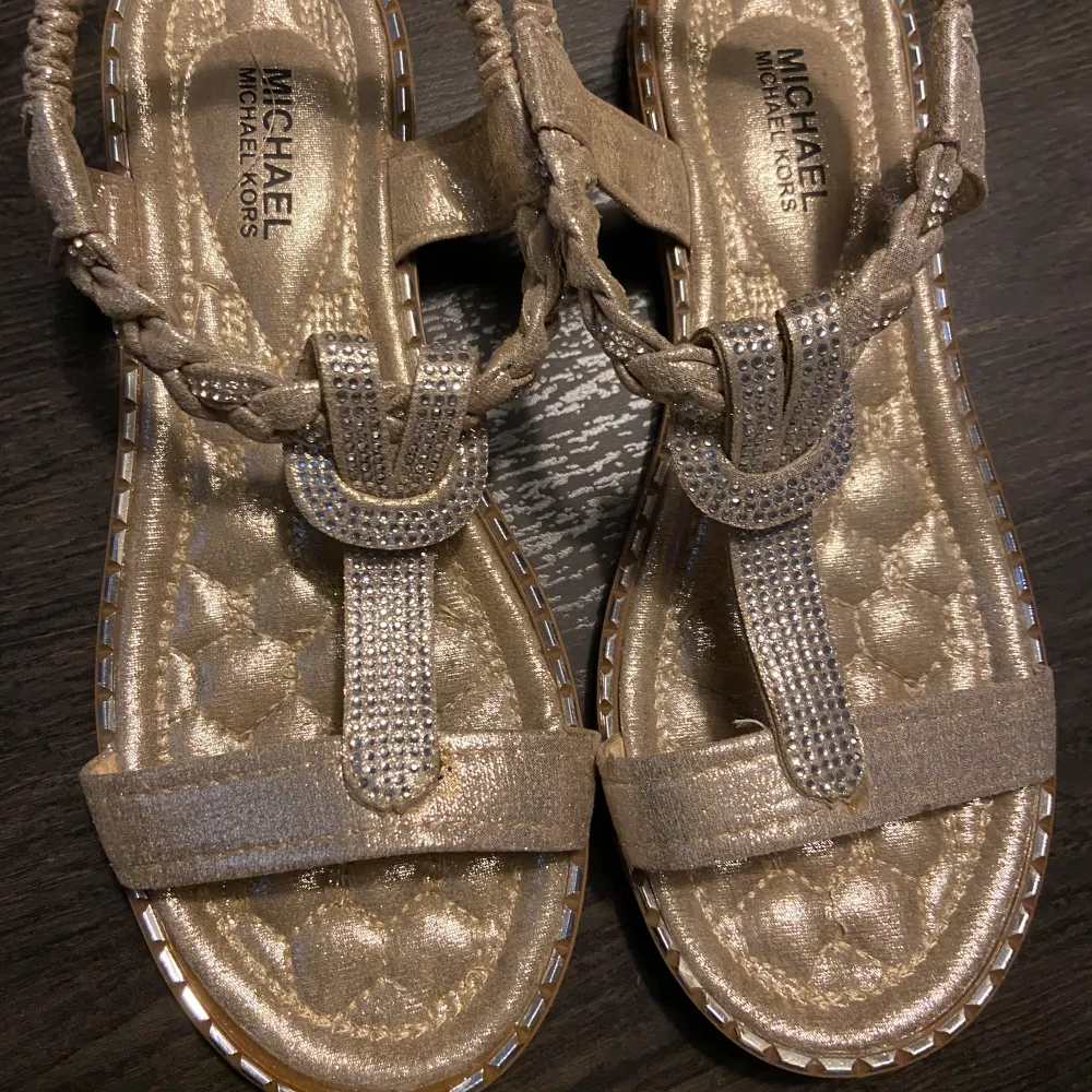 Storlek 40, fint skick  Använd fåtal gånger  Guldiga med silverdetaljer Dessa skor har inget spänne utan som en krinklad kardborrerem runt . Skor.