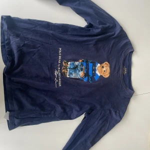 Polo Bear tröja av Ralph lauren - En Ralph lauren polo bear tröja i bra skick utan några defekter förutom att den är lite solblekt. Tröjan är i storlek 14-16. Ursprungspris: 1000kr Vårt pris: 350kr