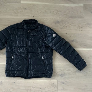 Moncler jacka  - Äkta. Säljer denna fina vår jacka. Litet hål fixat med tyg tejp man ser det knappt se bild 3 där av priset. Annars mycket bra skick! Passar både tjej och killar mest (killar) då det är en kill jacka. Skriv för fler bilder på detaljer etc. mörkblå 