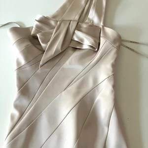 Karen Millen festklänning - Klassisk vacker siden klänning, champagne beige vit färg med fantastisk passform och design. Välfodrad dvs inga kanter eller dylikt syns och lite ”stel” och shaping.  Perfekt för bröllop, student eller bara fest. Passar en strl 36  Nypris 3000kr